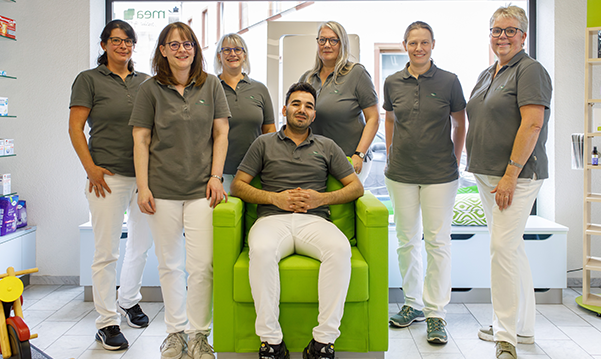 Das Team der Martinus Apotheke in Trier steht un den sitzenden Inhaber der Apotheke.
